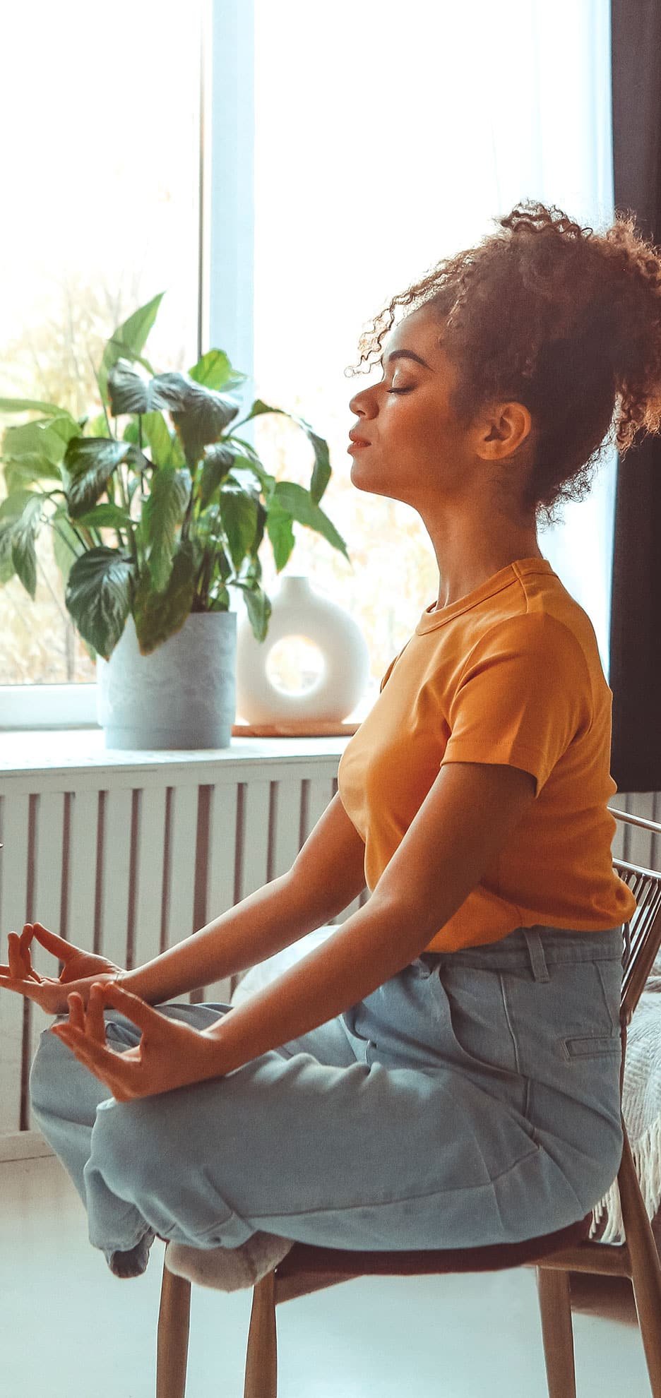 Mulher negra sentada na frente do computador meditando.